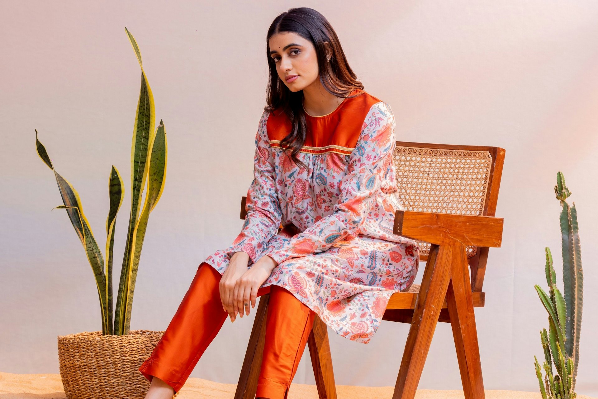 Woman models stylish clothing and sits on a chair.